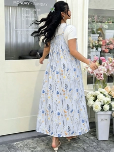 Detailansicht hellblaues Blumen-Trägerkleid mit weißem T-Shirt in einem Außengarten