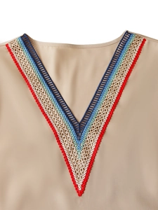 Détail du col en V avec broderies ethniques colorées et dentelle sur le chemisier kaki