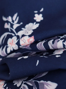 Gros plan sur le tissu en mousseline bleu marine avec motif floral blanc et rose