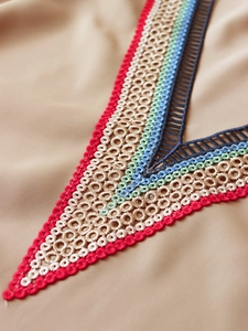 Détail de broderie colorée sur l'encolure en V d'un chemisier kaki pour femme