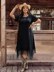 Detailed view of black short sleeve dress with asymmetric hem and fringe in bohemian style