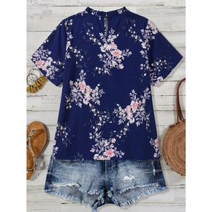 Chemisier à fleurs en mousseline bleu marine avec short en jean sur fond de bois blanc