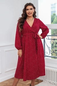 Détail d'une robe mi-longue rouge à pois avec col en V, lien à la taille et manches bouffantes
