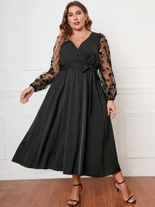 Dettaglio dell'abito nero taglie forti con maniche in mesh floreale e scollo a V profondo