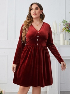 Detail of V-neckline and white contrast buttons on a red velvet long sleeve dress