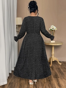 Detailed close-up of ruffle cuffs and white polka dot pattern on a black maxi dress
