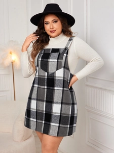 Détail d'une robe chasuble à carreaux grande taille avec pull blanc à col roulé et chapeau