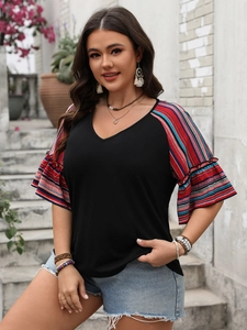 Detail of color block V-neck top featuring rainbow striped bell sleeves and black bodice
