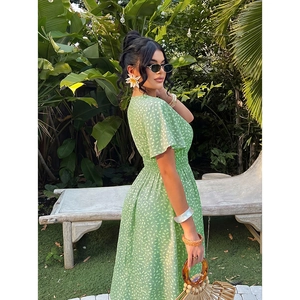 Light green floral V-neck dress with smocked waist and short sleeves in outdoor setting