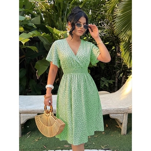Detail of light green V-neck floral summer dress with elastic waist in tropical garden