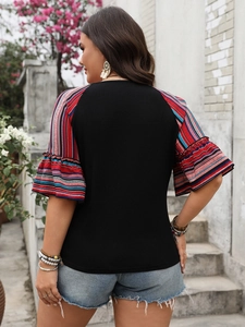 Rear view of plus size black top with colorful striped ruffle sleeves and patchwork design