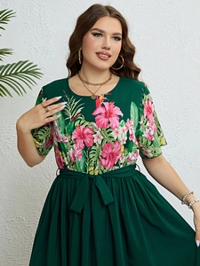 Détail de l'imprimé floral tropical sur robe vert foncé avec hibiscus et feuilles de palmier