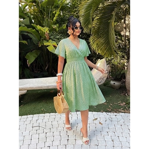 Close-up of a light green floral V-neck summer dress with delicate white flower patterns