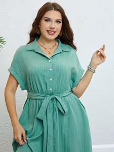 Detailed view of teal green short sleeve dress featuring vertical texture and belted waist
