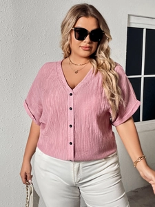 Detail of pink linen-textured shirt featuring a V-neckline and decorative black buttons