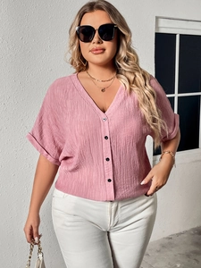 Close-up of pink linen-texture V-neck shirt featuring contrasting black buttons and casual fit
