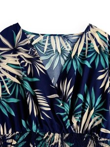 Close-up of deep V-neckline and smocked waist on a navy tropical palm leaf dress