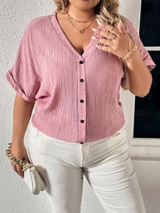 Detail of pink linen V-neck blouse featuring pleated texture and black buttons
