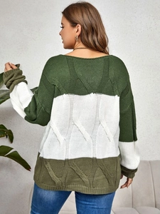 Back view of a woman wearing a color-block green and white cable knit sweater in a cozy room