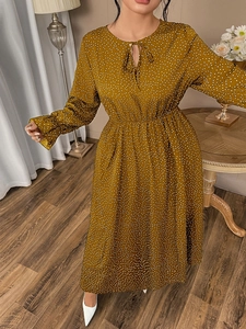 Detail of polka dot dress featuring tie-up V-neckline and ruffled elastic cuffs
