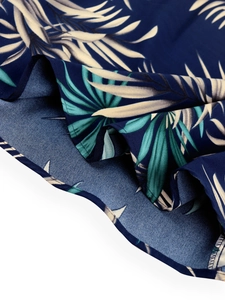 Macro shot of tropical palm leaf print fabric with navy blue base and high-quality overlock edges