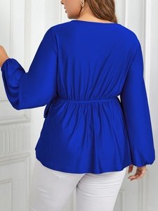 Détail du chemisier en satin bleu royal avec taille haute élastique et manches lanternes