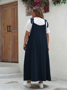 Detail of navy blue pinafore maxi dress with bow straps and vertical fabric texture