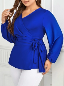 Détail de la blouse en satin bleu roi avec col en V, taille nouée et manches lanterne
