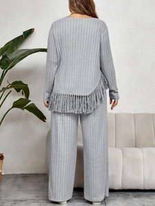 Detail showing the light grey ribbed fabric and asymmetric fringe hem on the back of the top