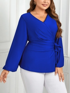 Détail de la blouse cache-cœur bleu roi avec col en V, nœud latéral et texture soie