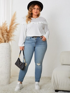 Detail of white long sleeve knit top featuring lace patchwork neckline and ruffle trim details