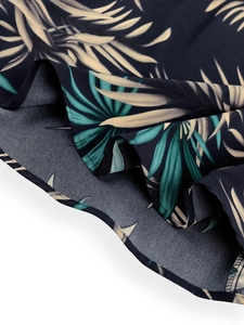 Detailed close-up of tropical palm leaf print fabric on a deep blue summer dress hem