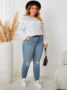 Close-up of elegant lace patchwork detailing and ruffle trim on white long sleeve top