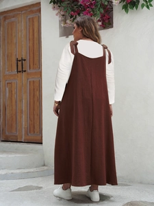 Back view of a brown maxi slip dress with wavy texture over a white long sleeve shirt