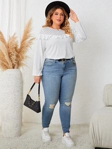 Detailed view of white knit top with lace ruffle and distressed blue skinny jeans