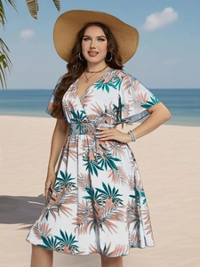 Close-up of tropical palm leaf print on a white summer V-neck dress with smocked waist design