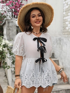 Détail du haut en broderie anglaise blanche avec trois nœuds en satin noir