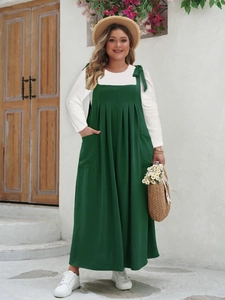 Detail of adjustable shoulder bows and pleated dark green plus size sundress fabric