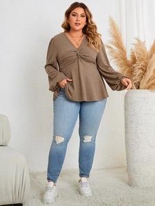 Detail of V-neck long sleeve top featuring knot front twist design in brown knit fabric