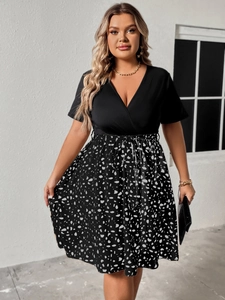 Detail of plus size V-neck dress featuring black bodice and abstract print skirt