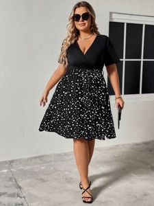 Detail of plus size V-neck dress featuring a black top and white polka dot print skirt