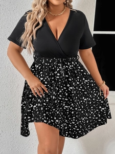 Detail of plus size V-neck dress featuring a black top and white floral patchwork skirt