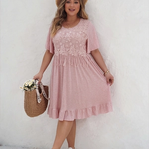 Détail d'une robe bohème rose grande taille avec dentelle au crochet et pompons décoratifs