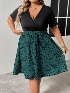Detail view of plus size V-neck dress featuring green floral print skirt and waist tie