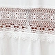 Detail shot of white linen skirt fabric with brown floral embroidery and lace trim