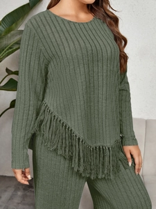 Detail of dark green ribbed knit fabric and asymmetric fringed hem on long-sleeve top