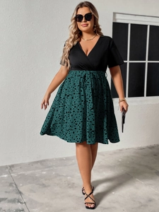 Detail of plus size v-neck dress featuring contrast stitching and polka dot print pattern