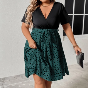 Detail view of plus size patchwork dress featuring V-neck and green polka dot skirt