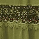 Detailed view of green cotton fabric with dark embroidery and hollow lace trim decoration