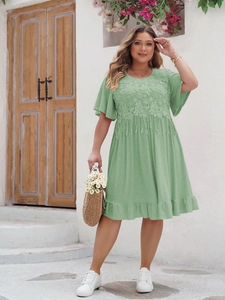 Détail de broderie florale et de pompons sur une robe bohème vert clair